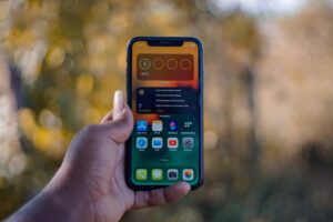 Dłoń trzymająca smartfon z widocznym ekranem głównym i widżetem baterii.