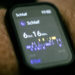 Zbliżenie na wyświetlacz smartwatcha pokazujący statystyki przespanej nocy w języku niemieckim.