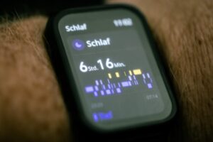 Zbliżenie na wyświetlacz smartwatcha pokazujący statystyki przespanej nocy w języku niemieckim.