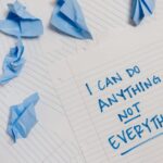 Kartka z napisem „I can do anything not everything” i zmięty niebieski papier.