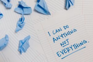 Kartka z napisem „I can do anything not everything” i zmięty niebieski papier.