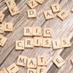 Drewniane kafelki z gry Scrabble układające się w słowa „BIG CRISIS”.