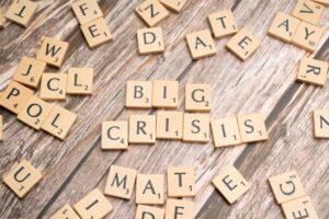 Drewniane kafelki z gry Scrabble układające się w słowa „BIG CRISIS”.
