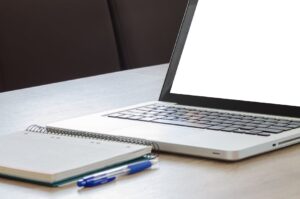otwarty laptop z białym ekranem, notatnik i długopis