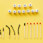 Napis „STOP BURNOUT” z klocków oraz rząd częściowo spalonych i całych zapałek.