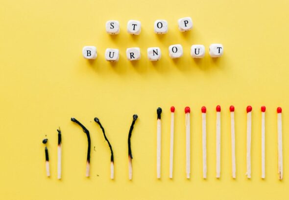Napis „STOP BURNOUT” z klocków oraz rząd częściowo spalonych i całych zapałek.